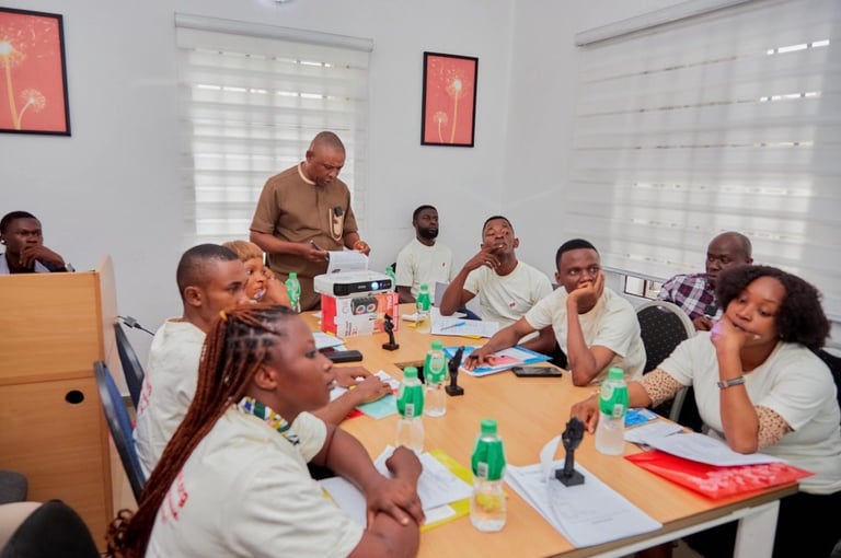 Group of people in white shirts sitting around a wooden table during a meeting or training session in a bright office room